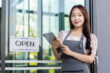 Female owner of coffee shop or restaurant turning round sign to open. Smiling young asian woman owner, employee retail coffee shop woman hand in setting sign board to open for welcome customer, reopen
