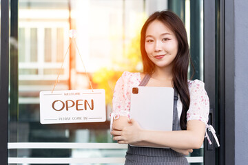 Female owner of coffee shop or restaurant turning round sign to open. Smiling young asian woman owner, employee retail coffee shop woman hand in setting sign board to open for welcome customer, reopen