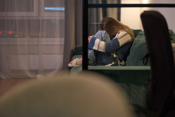 Fototapeta premium Female curled up on sofa indoors with head down