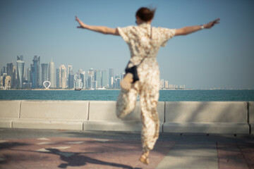 A happy girl jumps on a walk along the embankment