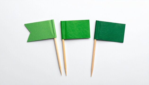 Three green toothpick flags with varied shapes and shades on white background.