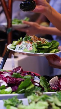 Pouring Salad Dressing Over Fresh Greens at Buffet Station