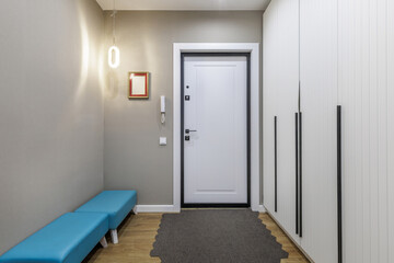 Bright Hallway with White Entrance Door and Blue Bench in Modern Apartment