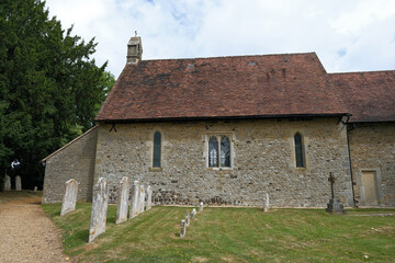 Fototapeta premium Ancient Stone Wall and Tiled Roof of St. Peter's Church with Gravestone Rows, Terwick
