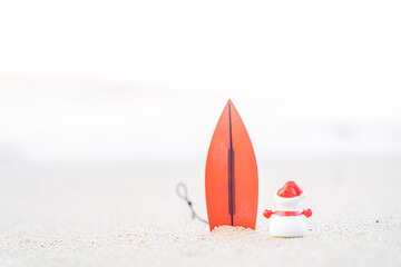 Sandy Christmas Snowman is watching the waves, standing on beautiful beach with a surf board - horizontal version in Patong Beach, Phuket, Thailand