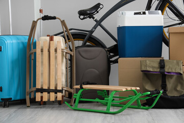 Sleds with suitcases and bicycle near light wall in room