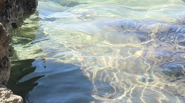 Closeup clear water rippling over rocky coast, transparent summer sea surface in tranquil scenery
