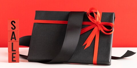 Sale sign with black gift box and red ribbon on a vibrant red background