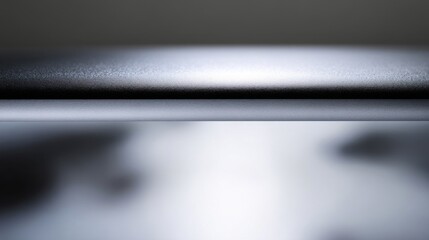 Close-up of a curved metallic surface with smooth contours, reflecting light in muted gray and silver tones,