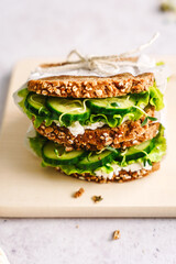 Sandwich mit Salat, Gurke und Vollkornbrot auf einem Holz Schneidebrett. Nahaufnahme, gesunde Ern&auml;hrung. 