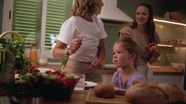 Warm and cozy scene of a happy multi generational family, with a grandmother, mother, and daughter, joyfully preparing a healthy meal together in their modern and inviting home kitchen