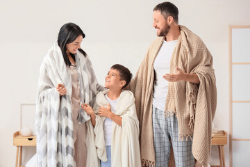 Obraz premium Happy parents and their little son with warm blankets in bedroom