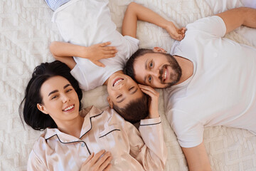 Obraz premium Happy parents and their little son lying on warm blanket, top view