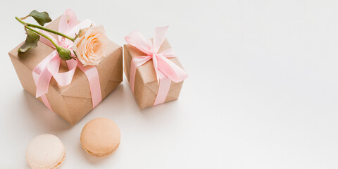 Two gift boxes with pink ribbons and macaron cookies on white background elegance