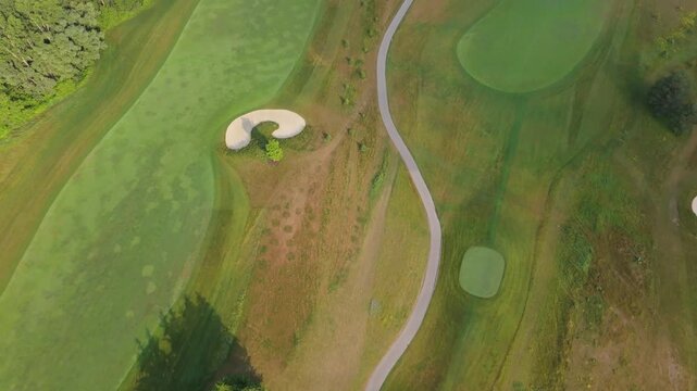 Top-down aerial shot of a golf course showing fairways, greens, bunkers, and winding cart paths, highlighting course design patterns and manicured turf.