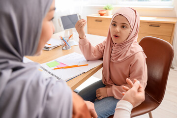 Muslim girl with her mother learning Arabic language at home