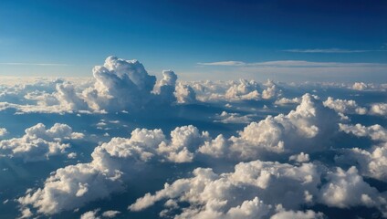 Aerial view of dramatic cumulus clouds over mountains. Blue sky with towering cloud formations above landscape. Scenic cloudscape horizon above distant mountain range.	