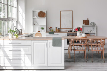 Interior of light kitchen with dining table, counters and shelf units