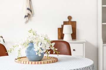 Vase with artificial flowers on dining table in kitchen