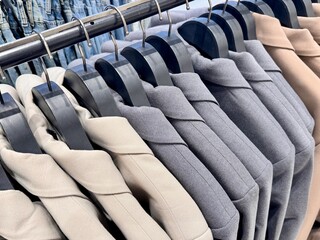 New stylish classic cut jackets in pastel shades are hanging on hangers in a clothing store