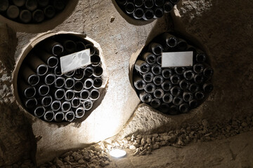 Rows of dusty wine bottles rest in circular stone niches, illuminated by soft cellar lighting, conveying tradition and vintage quality.