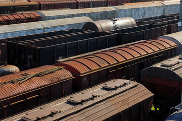 Top view of old, weathered freight train cars in a rail yard, showcasing industrial texture, strong lines, and urban transport infrastructure in natural daylight.