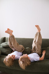 Two boys having fun, lying upside down on the couch, laughing