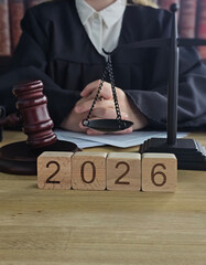 Courtroom scene showing judge with gavel, scales, and blocks marked 2026
