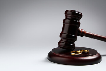 Judge's gavel with wedding rings on light background. Family law concept