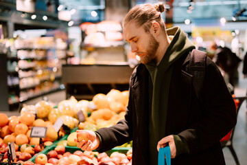 Man choosing fresh apples for healthy diet in supermarket, copy space.