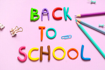 Text BACK TO SCHOOL made of play dough with stationery on pink background