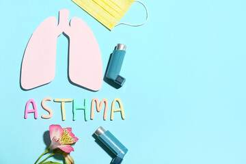 Word ASTHMA with inhalers, paper lungs and medical mask on blue background