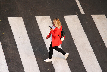 Mujer cruzando paso de cebra para peatones con teléfono móvil © Diego