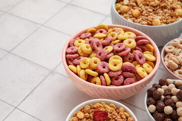 Bowls with different cereals on beige tile background, closeup