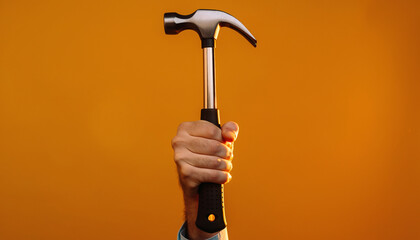 Hammering, Subject: Hand Holding Hammer, Location: Studio, Content Type: Photo, Environment: Solid Orange Background, Viewpoint: Close-Up, Concept: Strength