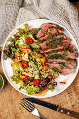 Grilled meat served with salad and vegetables on a white plate