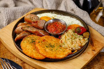 Breakfast plate with sausages, eggs, and sides at a dining table