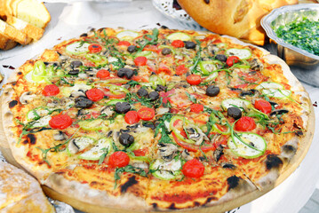 Artisan vegetarian pizza with zucchini, mushrooms, cherry tomatoes, olives, and arugula on thin crust. Represents wood-fired cooking, health-conscious fast casual dining, and outdoor food culture.