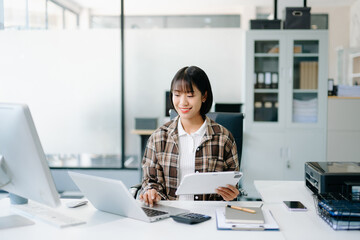 Beautiful Asian business woman typing laptop and tablet Placed at the table at the office