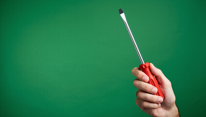 Hand Holding Red Screwdriver Against Green Background | Tools | DIY | Close-Up View | Creative Concept