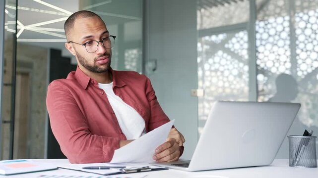 Businessman is tired of doing paperwork and doing tasks sitting at workplace in business office. Confused businessman having difficulty with work on documents. Exhausted male worker procrastinates