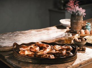 In a cozy Romanian kitchen, a wood-fired stove is at work. Freshly baked colaci and mucenici warm the rustic wooden table, filling the air with delightful steam and an authentic village atmosphere