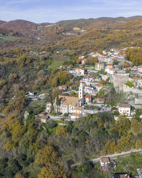Aerial view of the village nestled among the vibrant autumn foliage, with the church steeple piercing the skyline, Episcopia, Basilicata, Italy.