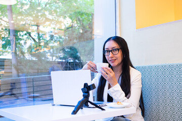 Woman drinking coffee recording content in cafe