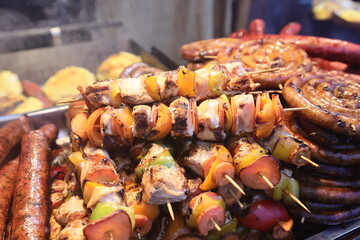 Grilled chicken kabobs prepared on grill at a Christmas market where various traditional dishes are served.
