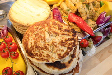 Pita and stuffed cabbage rolls prepared on grill at a Christmas market where various traditional dishes are served.