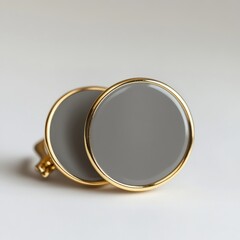 A pair of elegant gold cufflinks with gray circular stones on a plain surface