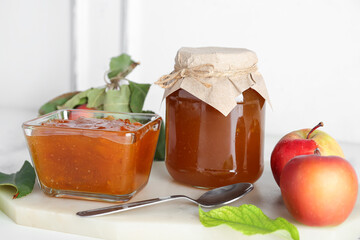 Board with sweet apple jam and fresh fruits on light table, closeup