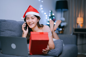 Happy woman making phone call holding gift at Christmas