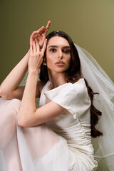 Fototapeta premium Young beautiful bride in elegant gown poses gracefully for a serene bridal portrait